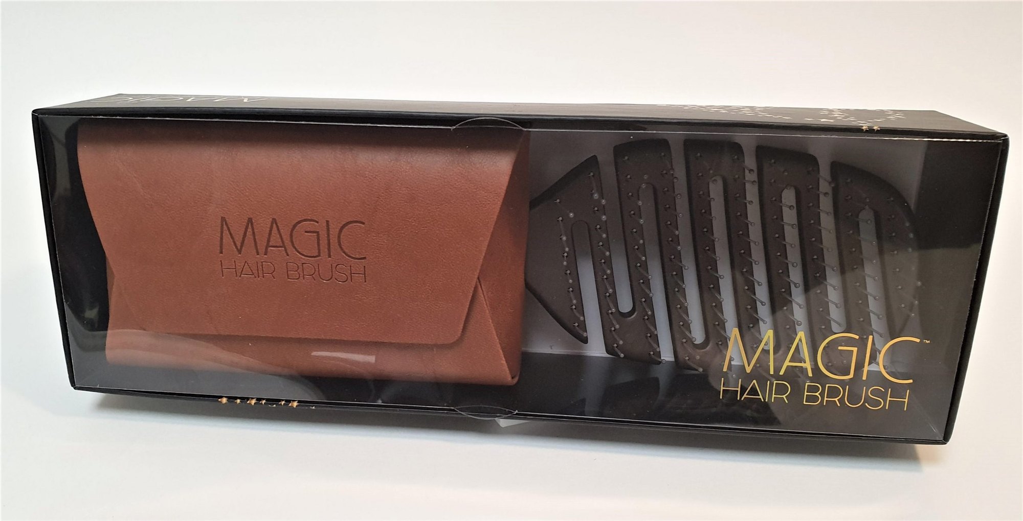 A tan bronze wallet embossed Magic Hair Brush, packed in the black retail box beside the brush behind clear film.